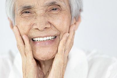 woman smiling after dentures helped restore her smile