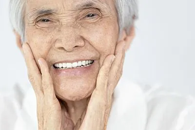 woman smiling after dentures helped restore her smile